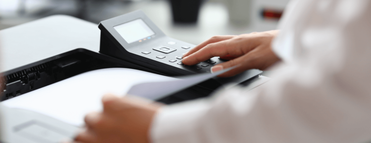 Closeup of business man with hands on top of desktop mfp, or multifunction printer in an office