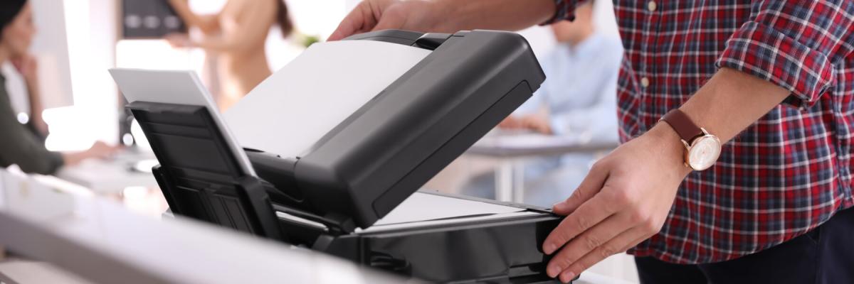 person lifting the top of a multifunction printer